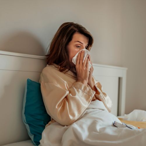 Woman in her 40's struggling with her allergies and poor immunity in bed